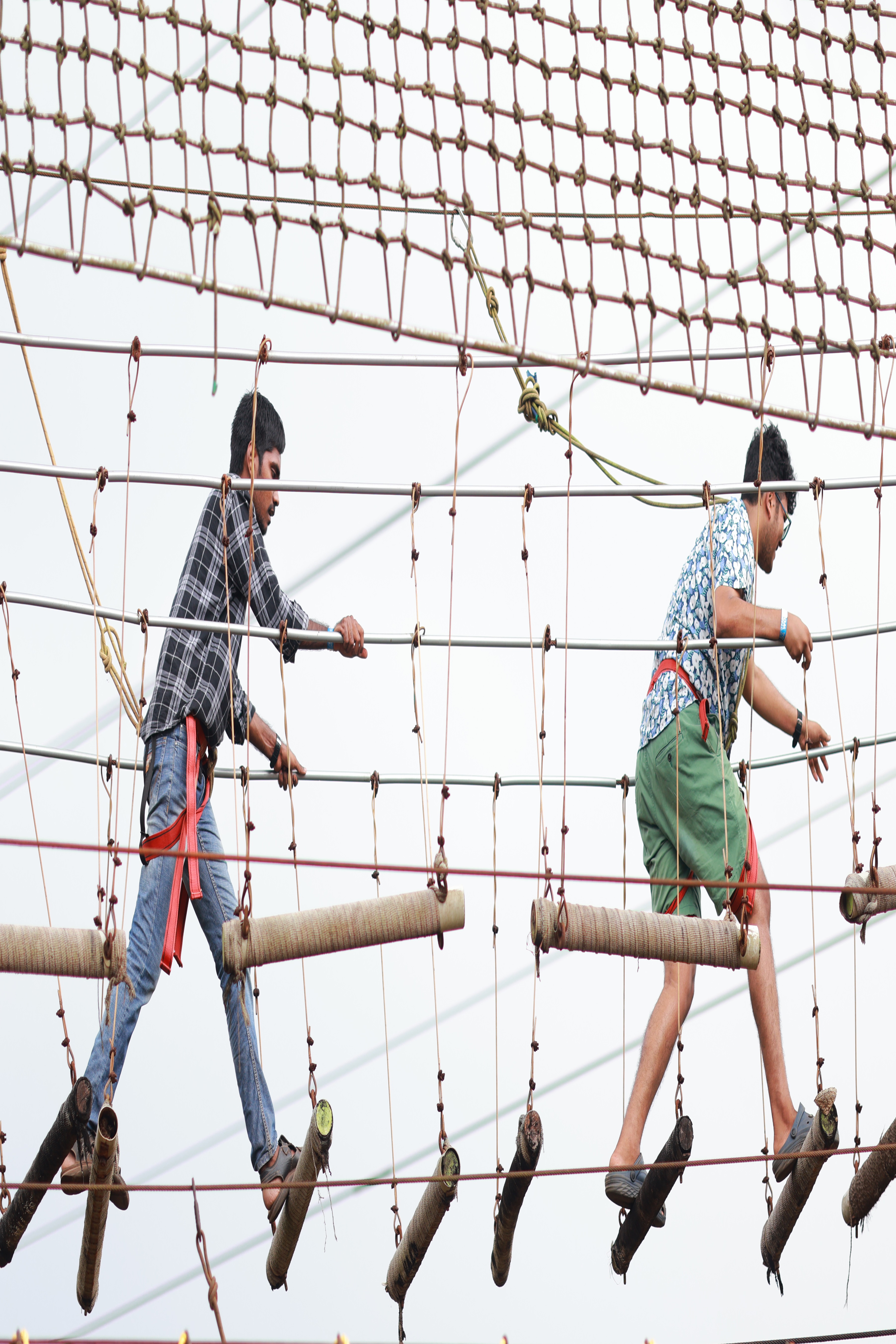 Visitors navigating a suspended log swing bridge at Goa Aqua World, enjoying a fun-filled adventure activity that tests balance and coordination.