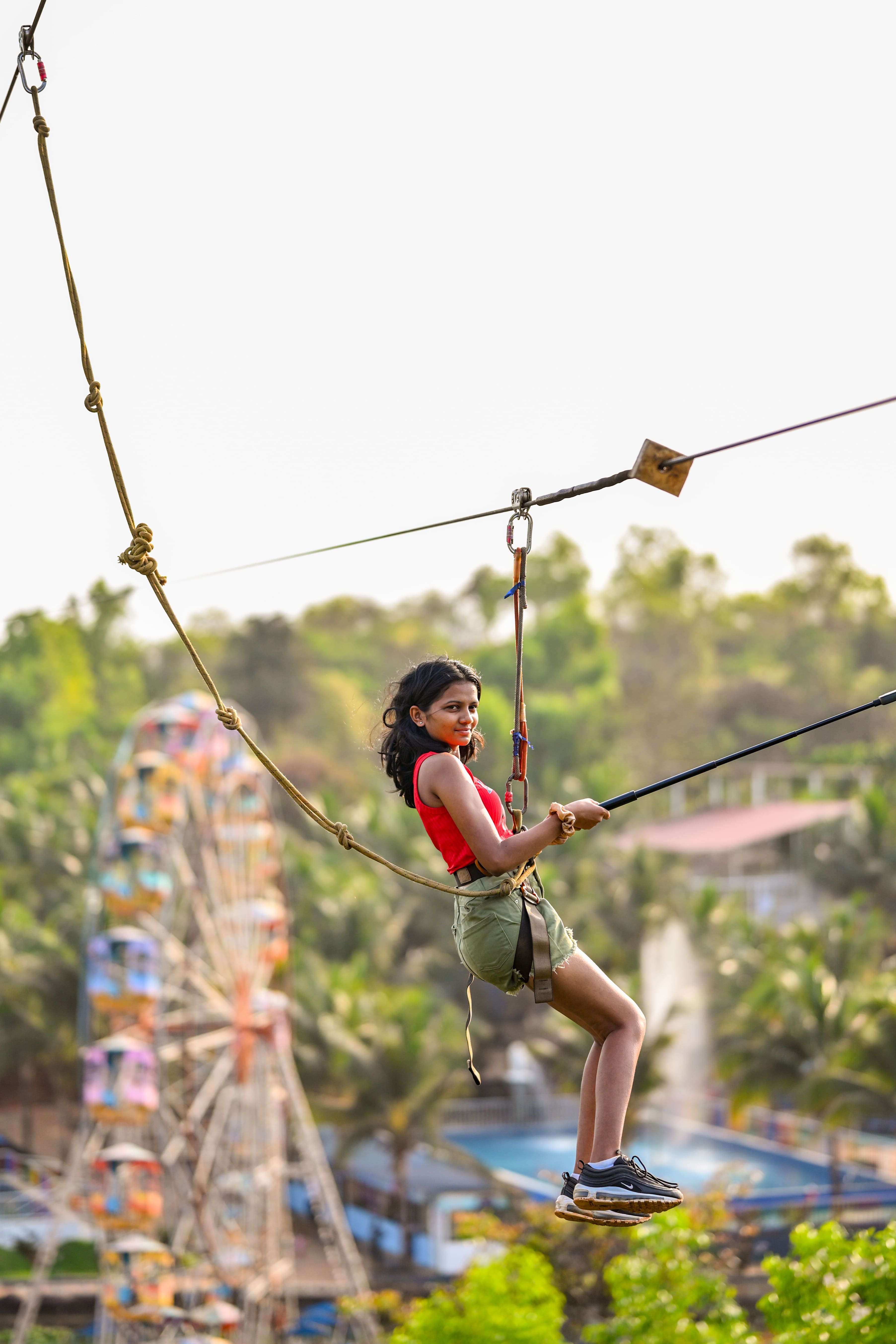 Thrilling zip-lining experience with a visitor enjoying the aerial view of lush greenery at Goa Aqua World.